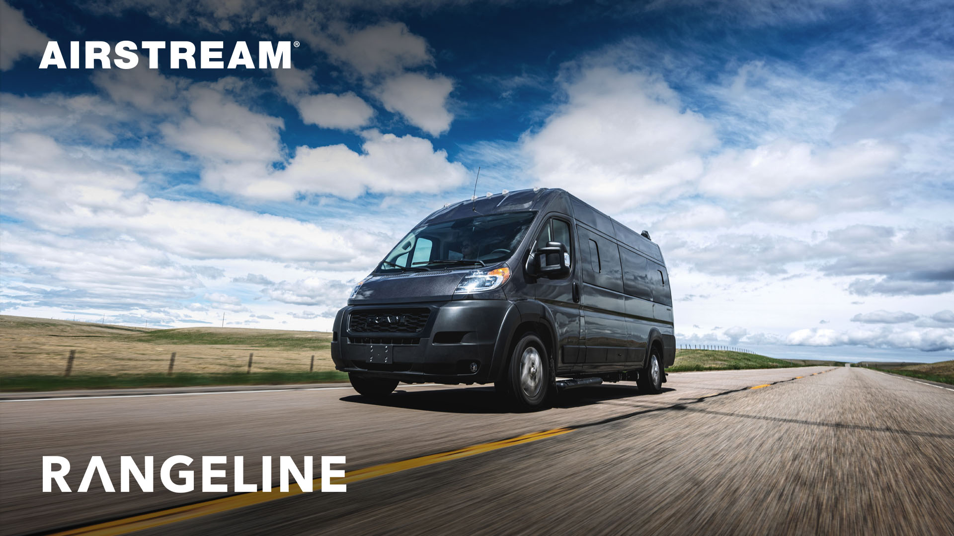 A black Airstream Rangeline van driving on an open road under a blue sky with clouds.