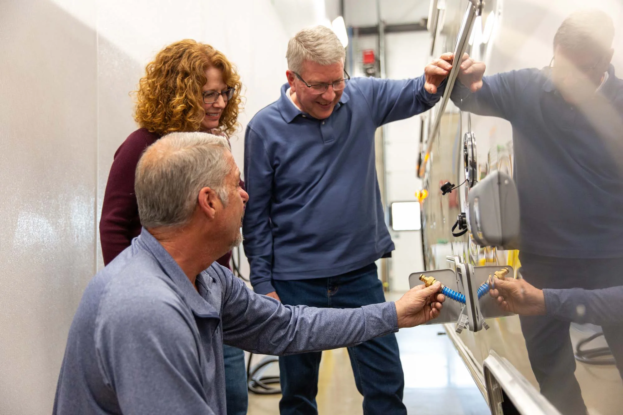 Three people in a workshop examining equipment on a panel, engaging and discussing its features.