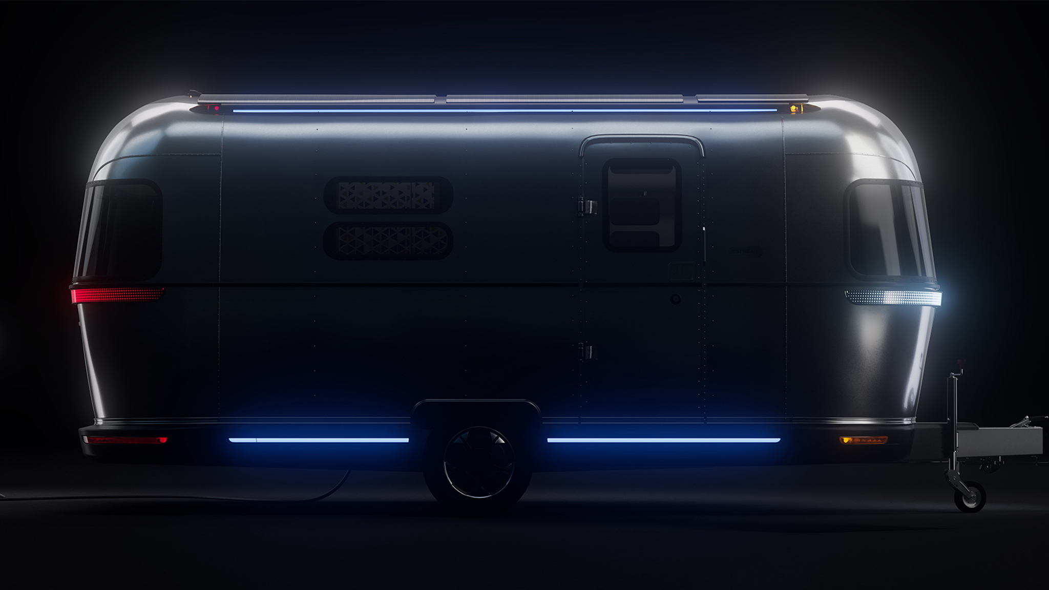 A shiny silver travel trailer is shown in a dark setting, illuminated by blue and red LED lights along its bottom and edges, with a door and small windows visible on its side.