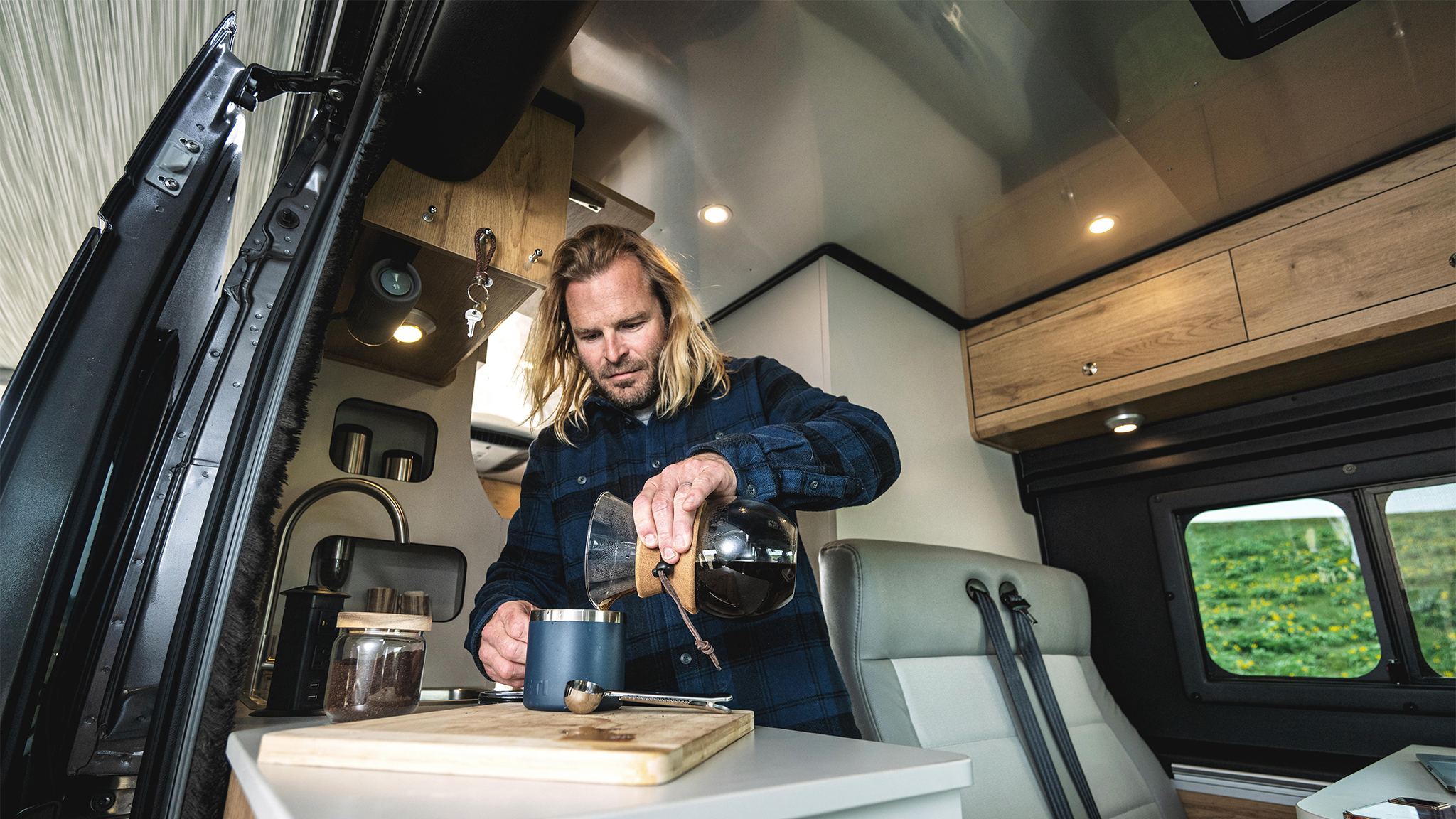 A man making coffee in the galley of his Airstream Rangeline Class B.|2024-Rangeline-Curbside-Silver|The front of the metallic Rangeline Airstream Class B|MOLLE panels inside of the rear door in the Airstream Rangline Class B Motorhome|A man making coffee in the galley of his Airstream Rangeline Class B.|The front view of the Airstream Rangeline Class B Motorhome|Rangeline Carpet-Kit|Rangeline-Carpet-Kit