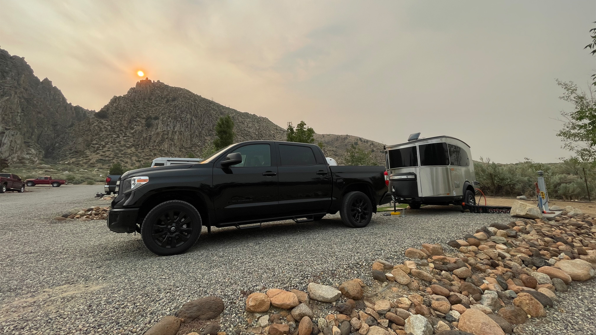 Black truck parking an Airstream Basecamp travel trailer at a campground with mountains and a sunset in the background|Airstream Basecamp travel trailer parked out west with mountains and trees in the background|James Schaal with his refinished 1966 Caravel|An Airstream Basecamp travel trailer parked next to another Airstream travel trailer at a campground out west.|james schaal standing in the moutains.|Airstream Basecamp travel trailer parked at a campground under a tree out west.|A black truck towing an Airstream Basecamp travel trailer|Black truck parking an Airstream Basecamp travel trailer at a campground with mountains and a sunset in the background