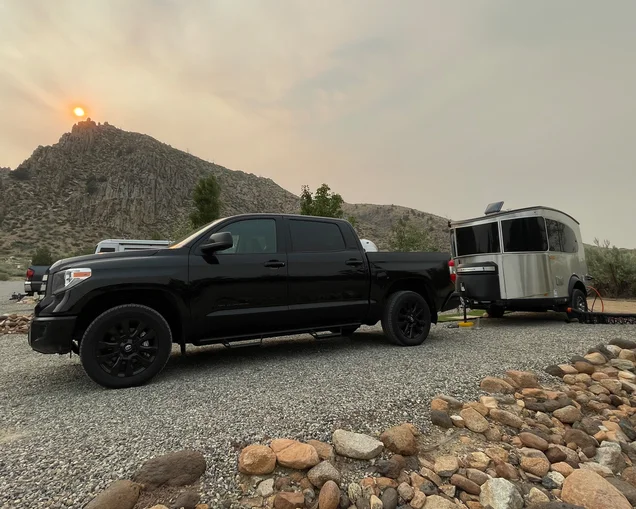 Black truck parking an Airstream Basecamp travel trailer at a campground with mountains and a sunset in the background|Airstream Basecamp travel trailer parked out west with mountains and trees in the background|James Schaal with his refinished 1966 Caravel|An Airstream Basecamp travel trailer parked next to another Airstream travel trailer at a campground out west.|james schaal standing in the moutains.|Airstream Basecamp travel trailer parked at a campground under a tree out west.|A black truck towing an Airstream Basecamp travel trailer|Black truck parking an Airstream Basecamp travel trailer at a campground with mountains and a sunset in the background