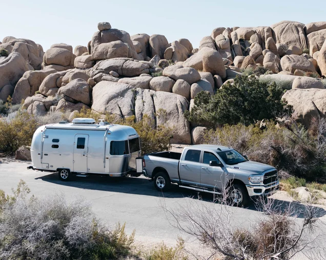 Surprising-Savings-Feature-Image|An Airstream caravel travel trailer being towed by a truck in the desert.