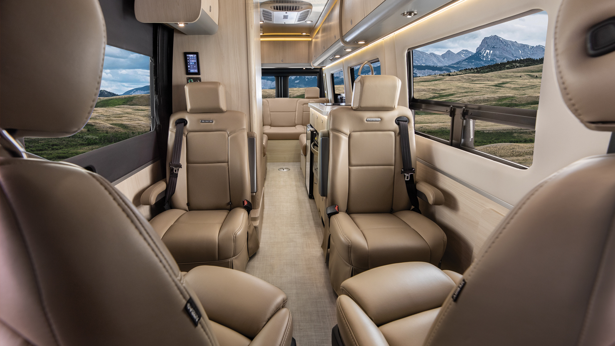 Luxurious van interior with beige leather seats, ambient lighting, and large windows showing a scenic mountain view.