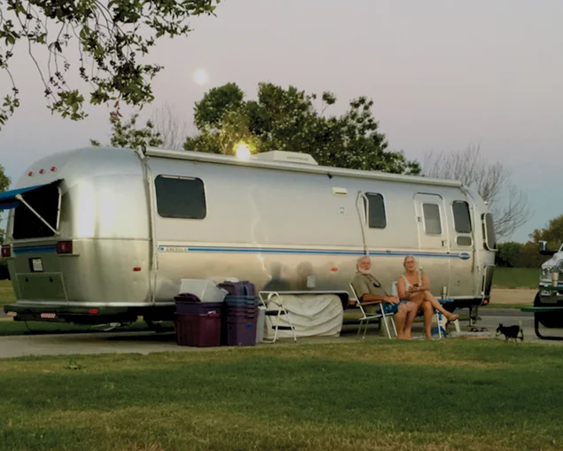 Jim and Carmen sitting outside of their Airstream Travel Trailer|An Airstream tire that is blown out on the side of the road|Jim fixing the tire on his Airstream Travel Trailer on the side of the road|Jim and Carmen when they were magicians|Jim using a sword box|Jim and Carmen looking out at a river|Living-in-Beauty-Champaigne|Living-in-Beauty-Champaigne|Living-in-Beauty-Blow-Out|Airstream travel trailer parked at campground|Jim and Carmen sitting in a hot spring|Living-in-Beauty-Back-Window|Jim and Carmen sitting at a River|Jim and Carmen sitting outside of their Airstream Travel Trailer