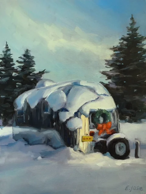 A snow-covered vehicle with a wreath on the front is parked in a snowy landscape with evergreen trees in the background.