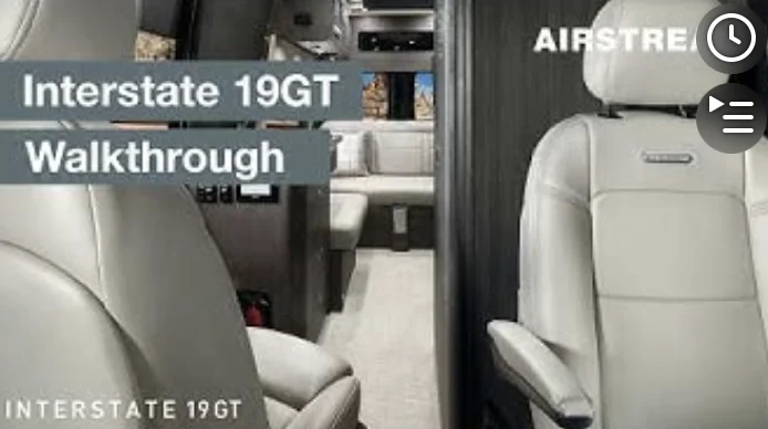 Interior of an Airstream Interstate 19GT RV with two white seats, showing the vehicle's spacious design. Text: "Interstate 19GT Walkthrough."