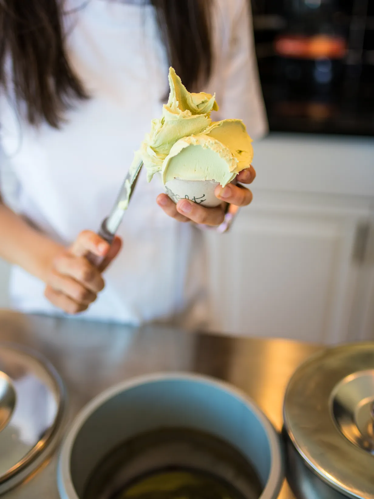 Viki the gelato queen, scoops artisanal organic mint gelato into a large cup. Ideal for catering events