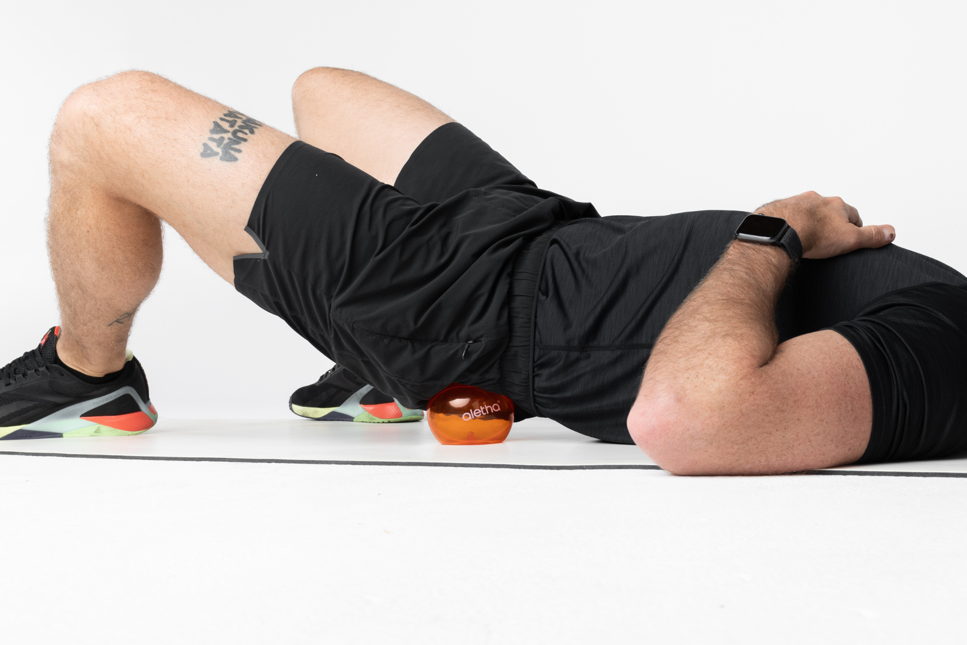 man using ball to massage piriformis muscle