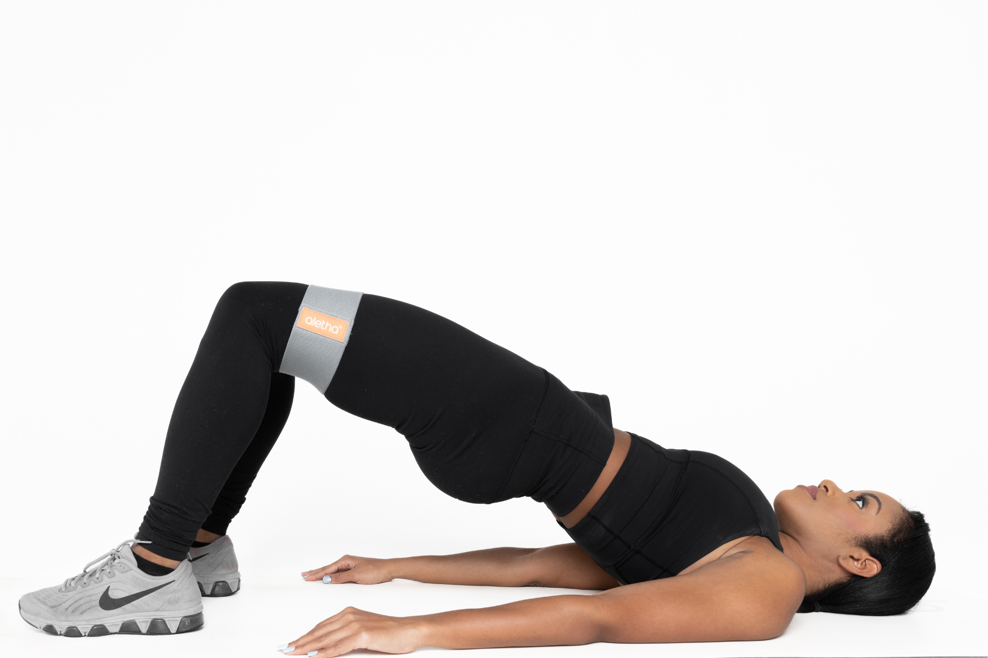 null woman performing glute bridge exercise with resistance band around her knees