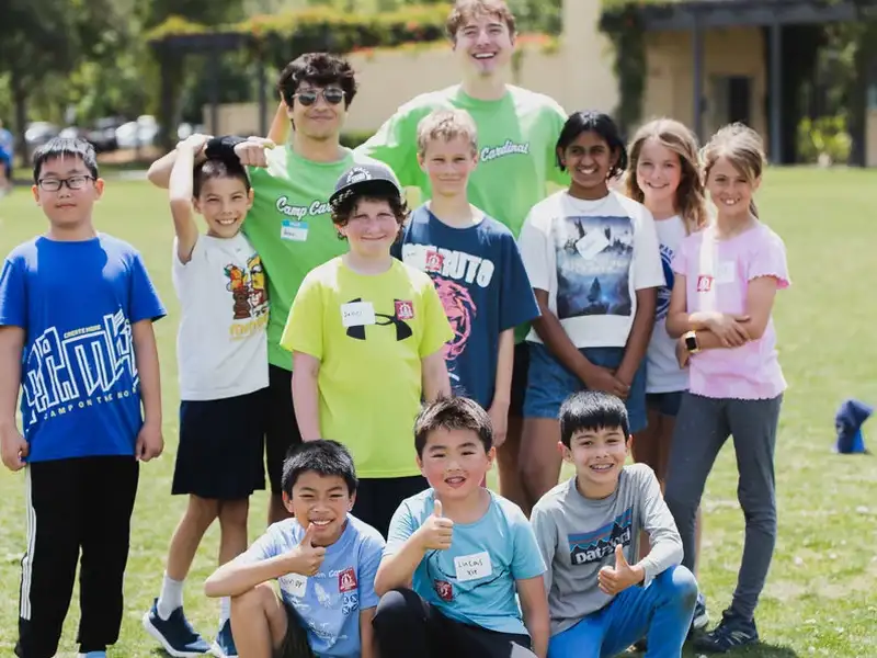 A group of children poses together on a sunny lawn.