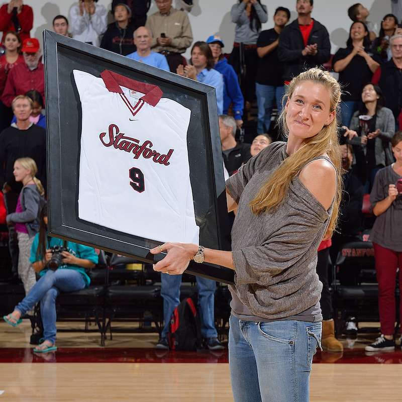 Kerri Walsh Jennings holds a framed Stanford jersey number 9 on the court.