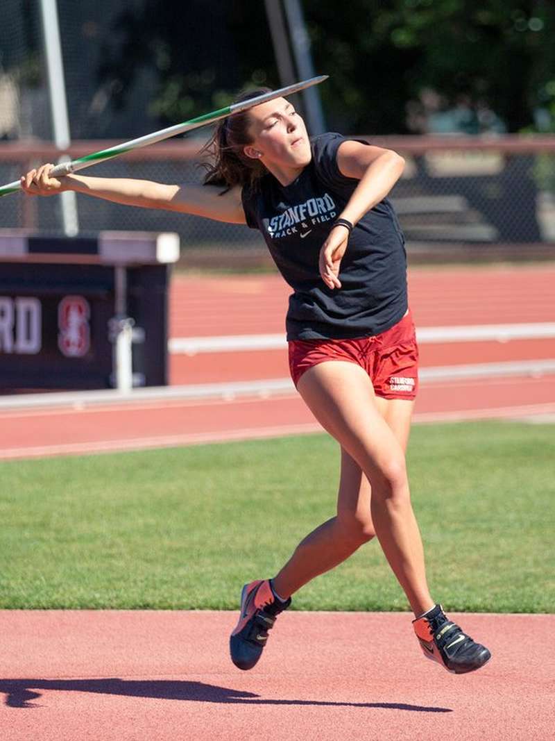 Virginia Miller prepares to throw a javelin on a sunny outdoor track.