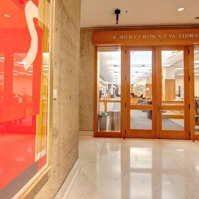 The entrance to the Robert Crown Law Library features wooden doors and colorful artwork on display nearby.
