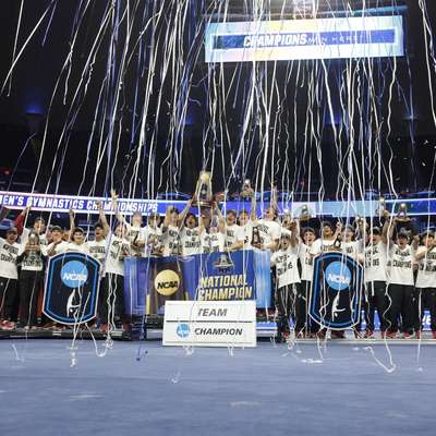 The men's gymnastics team poses for a photo while celebrating their NCAA Championship win.