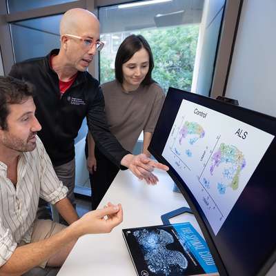 Jacob Blum, Aaron Gitler and Olivia Gautier gather around a monitor displaying cell cluster data comparing control and ALS samples.