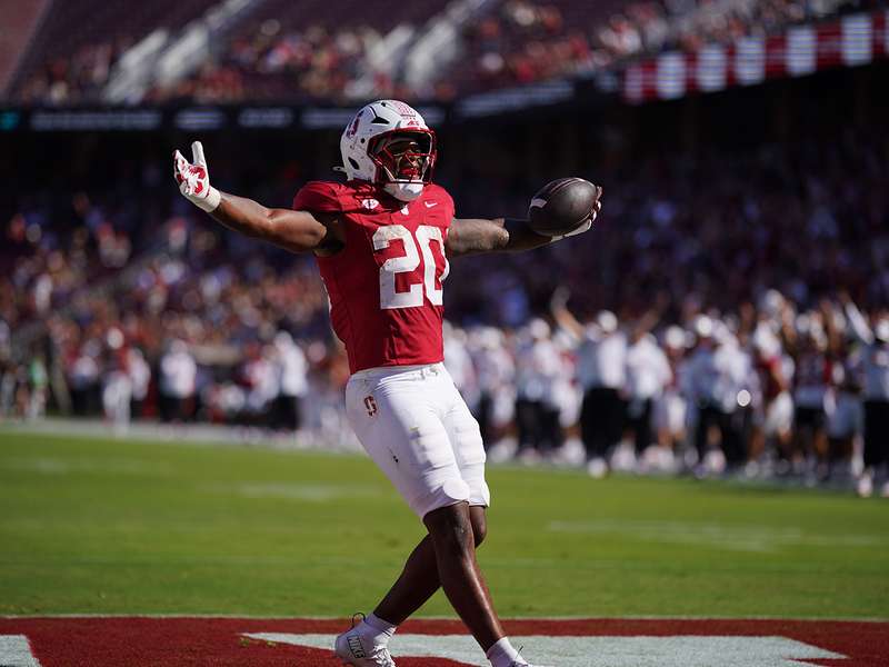 Micah Ford raises his arms in celebration in the end zone after scoring a touchdown during a football game.