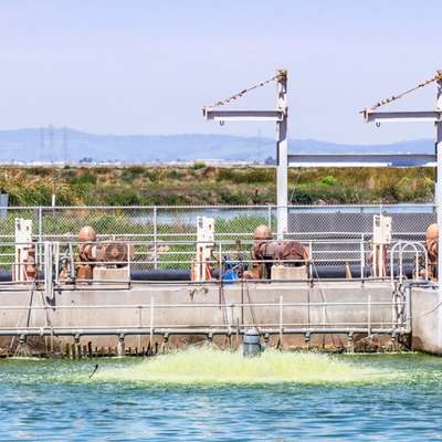 Pumps and pipes line a water treatment basin, where an aerator churns the water.