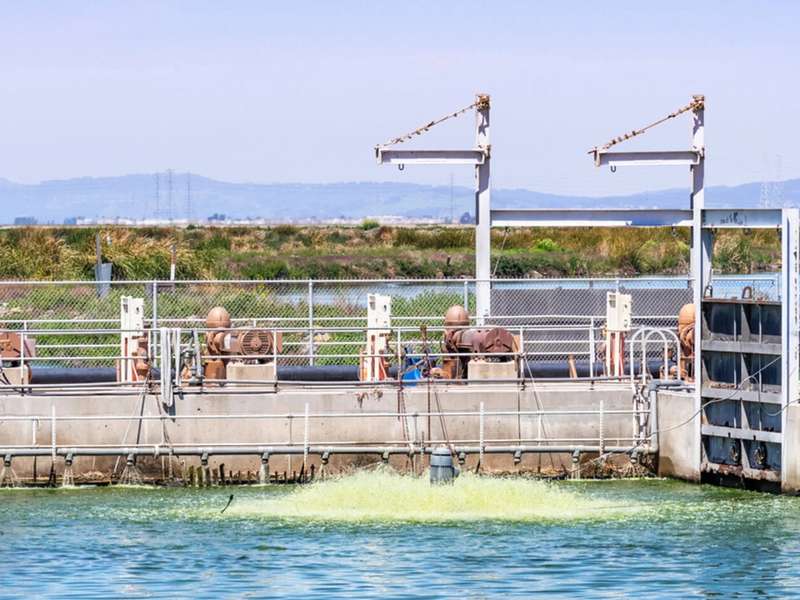 Pumps and pipes line a water treatment basin, where an aerator churns the water.