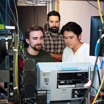 Portrait of the three researchers surrounded by instrumentation.