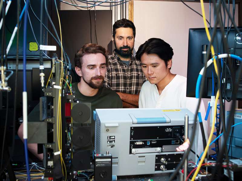 Portrait of the three researchers surrounded by instrumentation.
