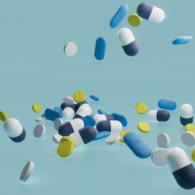 Colorful capsules and tablets scattered against a light blue background.