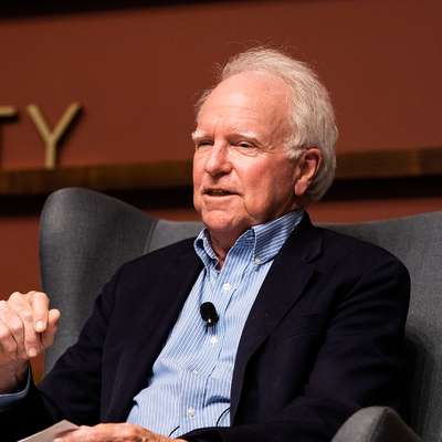 Robert Hall gestures while speaking in an armchair at a panel discussion.