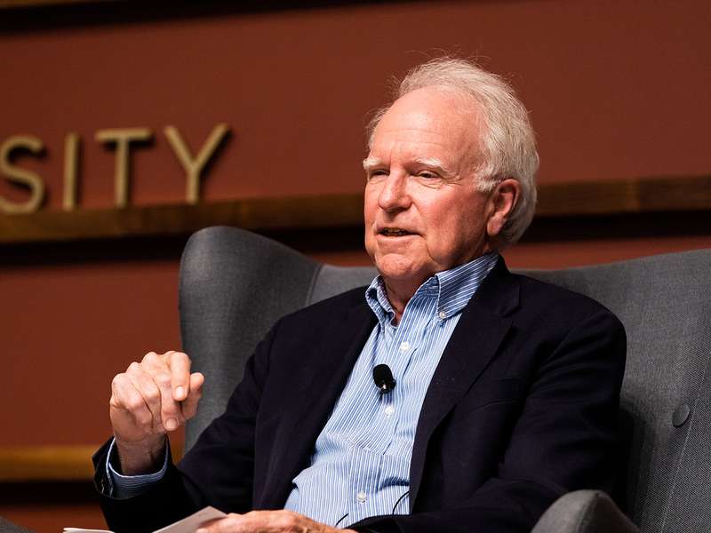 Robert Hall gestures while speaking in an armchair at a panel discussion.