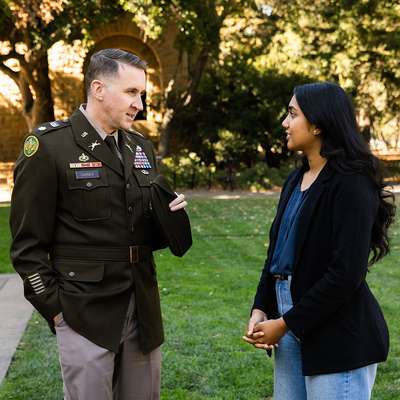 National Security Affairs Fellow Lt. Col. Thomas N. Garner and his mentee Anika Yadav speak outside Hoover Tower on Stanford campus.