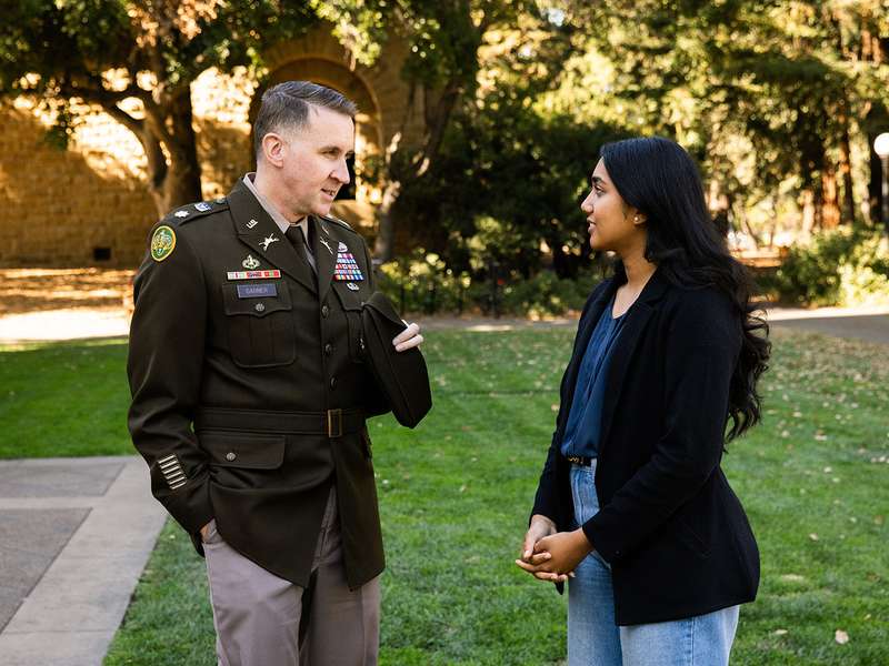 National Security Affairs Fellow Lt. Col. Thomas N. Garner and his mentee Anika Yadav speak outside Hoover Tower on Stanford campus.