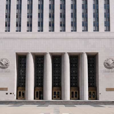 Art Deco federal courthouse entrance with tall columns and two American flags.