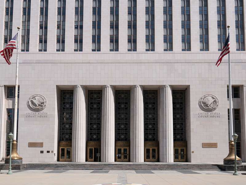 Art Deco federal courthouse entrance with tall columns and two American flags.
