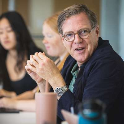 Mitchell Stevens sits at a table, looking toward the side to engage in a conversation.