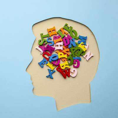 Illustration of colorful letters filling a paper head silhouette, symbolizing language and thought.