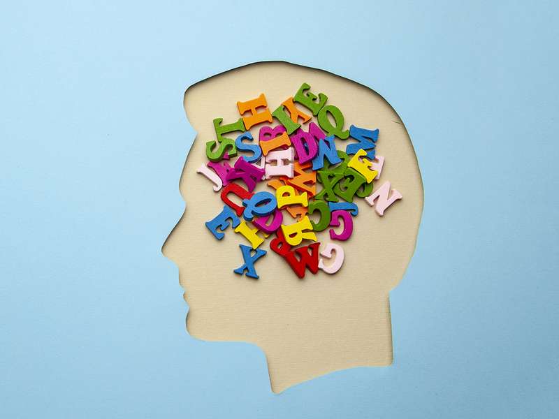 Illustration of colorful letters filling a paper head silhouette, symbolizing language and thought.