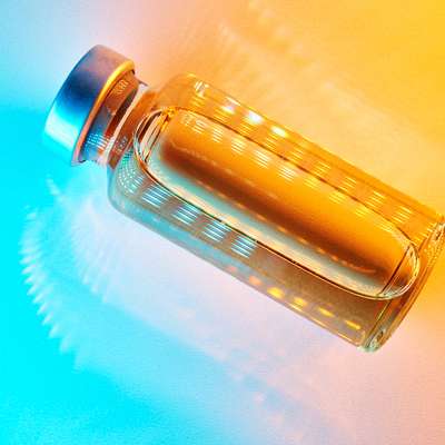 A glass bottle filled with liquid is illuminated with vibrant orange and blue lighting effects.
