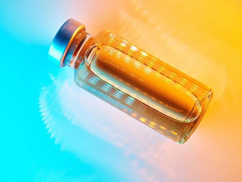 A glass bottle filled with liquid is illuminated with vibrant orange and blue lighting effects.