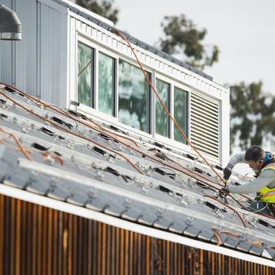 Image of a person installing the foundation for solar panels on the roof of the O'Donohue Family Stanford Educational Farm.