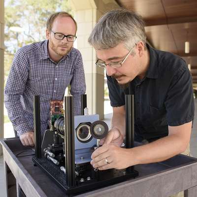 Assistant prof. Gordon Wetzstein, left, and postdoctoral scholar Donald Dansereau with a prototype of the monocentric camera that captured the first single-lens panoramic light fields.