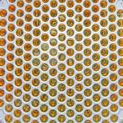 Close view of a circular array of hundreds of gold-toned light sensors packed into a white panel.