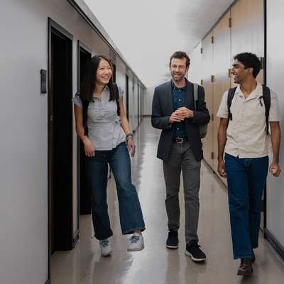 Mary Zheng, Brian Coyne, and Arjun Ayyappan walking together down a corridor. 