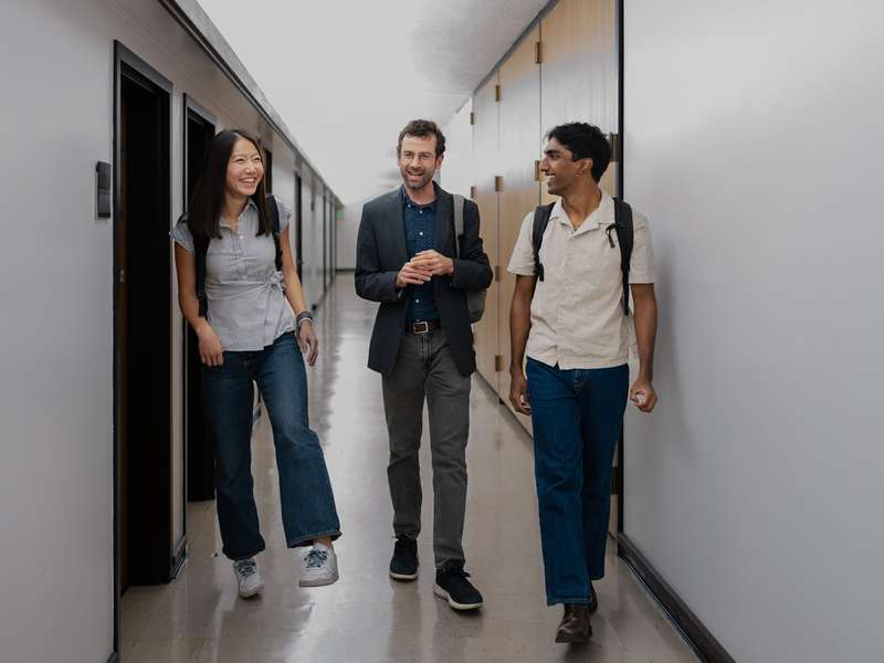 Mary Zheng, Brian Coyne, and Arjun Ayyappan walking together down a corridor. 