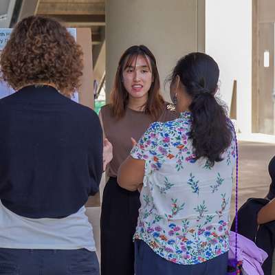 Student presents a scientific poster on brain imaging and memory to a small group at an outdoor conference session.