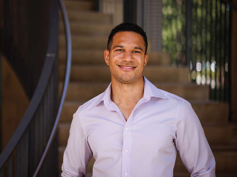 Julian Nyarko standing in front of a staircase and posing for a profile photo.