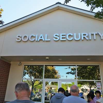 People waiting in line in front of a Social Security building.