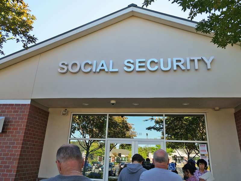 People waiting in line in front of a Social Security building.