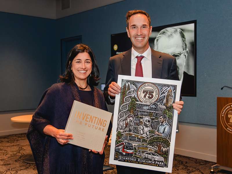 Tiffany Griego and Jonathan Levin, holding the book “Inventing the Future” and an illustrated Stanford Research Park 75th-anniversary poster.