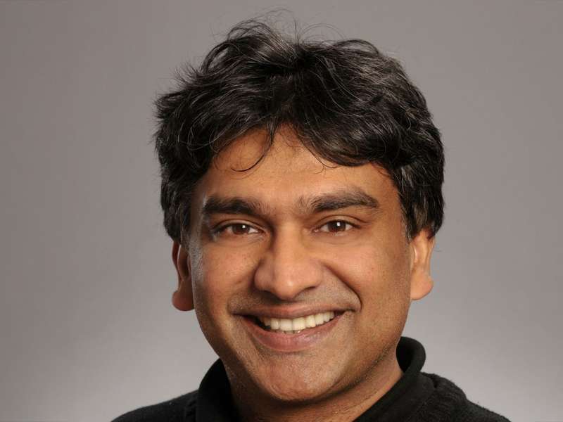 Bali Pulendran smiling into the camera against a gradient gray background.