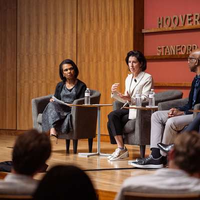 A panel discussion at the Hoover Institution features four speakers engaged in conversation in front of an audience.
