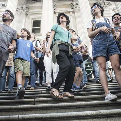 A group of people standing on steps, holding signs and participating in a movement.